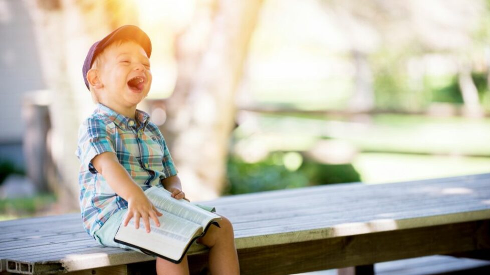 boy sitting on bench while holding a book