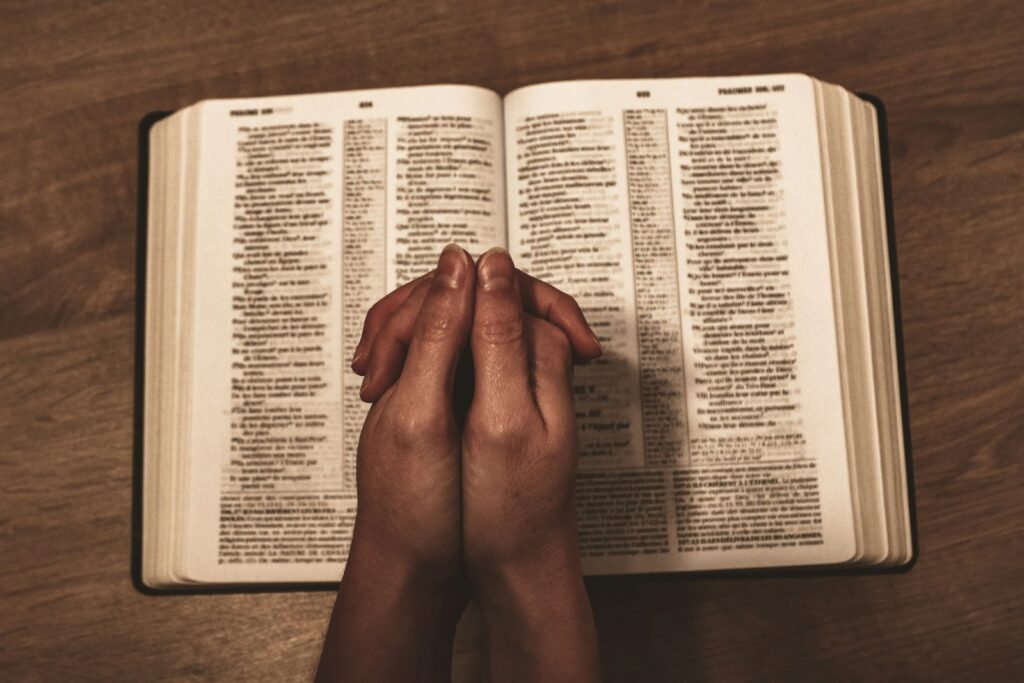 person holding book on brown wooden table